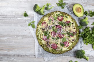 Food, Crust Broccoli base low carbs keto pizza with salami, avocado on vintage newspapper. Top view