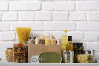 Set of uncooked foods on pantry shelf prepared for disaster emergency conditions on brick wall
