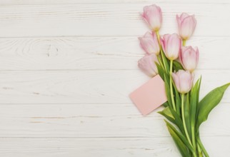 Tulip bouquet with empty card wooden table. High resolution photo