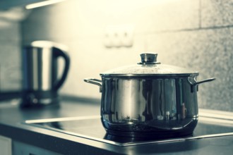 A saucepan with a glass lid is placed on an electric cooker