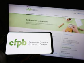 Stuttgart, Germany, 09-18-2022: Person holding mobile phone with logo of US Consumer Financial