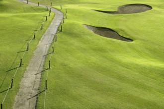 Golf course green grass hill field with holes and track way