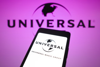 In this photo illustration, the Universal Music Group logo is displayed on a smartphone screen and