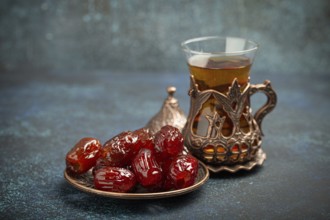 Breaking fasting with dried dates during Ramadan Kareem, Iftar meal with dates and Arab tea in