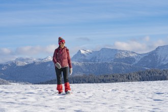 Pretty active senior woman snowshoeing in the Allgäu Alps near Oberstaufen with a view of the