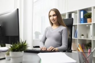 Pregnant businesswoman working her desk computer