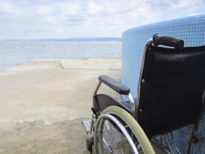 Empty wheelchair on an accessible beach with pool for assistance to help people with disabilities