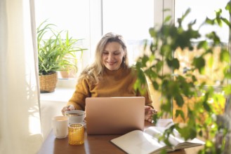 Joyful happy middle-aged woman chatting online on laptop at home, making video call via internet,