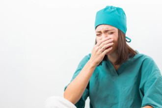 Emotional nurse in teal uniform crying on a white background