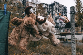 Soft toys are dried after washing against the background of a burnt-out multi-storey building in