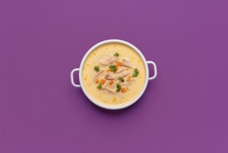 Top view with a bowl of chicken soup, greek recipe with lemon juice and vegetables