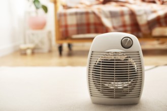 Fan heater on the floor in living room with sofa at background