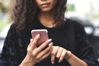 Close up portrait of beautiful young african american woman reading text message on mobile phone at