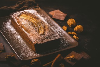 Homemade vegan banana bread or cake with nuts, chocolate and cinnamon on brown background