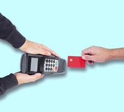 top view of person paying using credit card or debit card, holding card against credit card reader