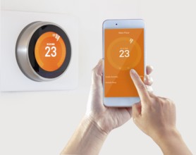 Smart Thermostat and a person setting up the temperature smart device hand hold on a white