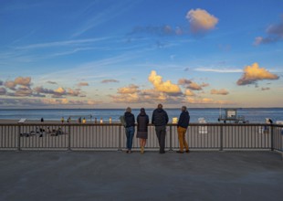 Holidaymakers stand on the promenade in the evening light and look out to sea, Hörnum, Sylt