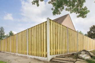New wooden fence as corner around garden of home