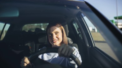 Woman smiling while confidently driving a car in daylight