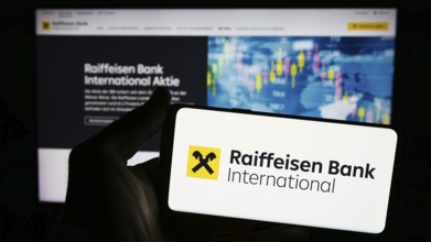 Stuttgart, Germany, 03-16-2024: Person holding smartphone with logo of Austrian company Raiffeisen