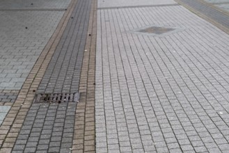 Deserted paved pedestrian zone with gully cover