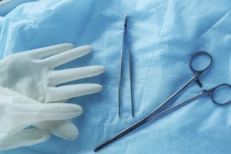 Surgical tools and gloves on blue cloth, showing readiness for medical procedures