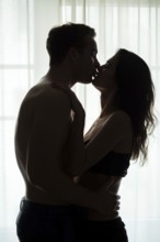 Couple kissing near window. Man and woman in darkness. Sweet taste of your lips