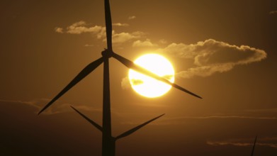 Beautiful sunrise dawn landscape with windmills or wind turbine on wind farm in rotation to