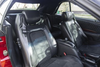 Spacious car interior with black leather seats and headrest, bathed in sunlight