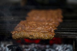 Making Spicy seekh kebabs are being grilled on burning charcoal in barbeque at a dinner party at