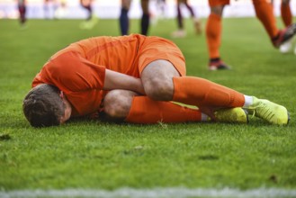 The injured footballer lies on the pitch.