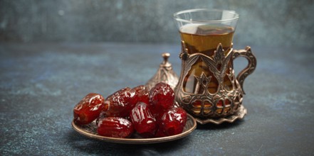 Breaking fasting with dried dates during Ramadan Kareem, Iftar meal with dates and Arab tea in