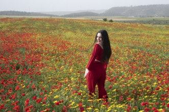 Young happy smiling woman wearing red dress in spring field