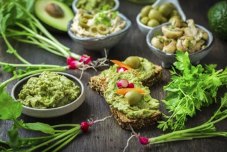 Wholemeal bread with avocado spread and vegetables on wooden kitchen table