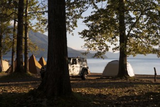 Tents and a white jeep with mountains in the background, sunrise at the lake, Shikotsu-Lakeside