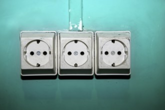 Aged electric plug socket dirty over green wall