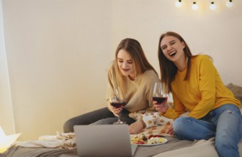 Two cute happy funny women friends having fun together, arranging home cinema evening, watching