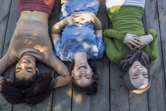 Multiracial young teen female friends resting in the park after sport training laughing and having