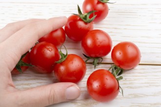 Red ripe tasty fresh cherry tomato in hand in view
