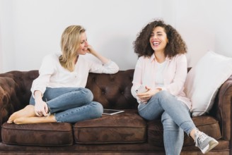 Cheerful women with technologies speaking sofa