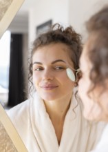 Woman looking mirror doing face massage 3