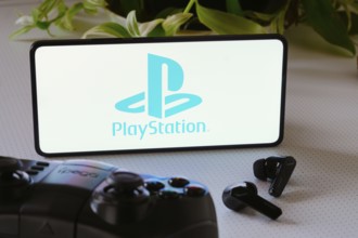 In this photo illustration, the PlayStation logo is displayed on a smartphone screen, next to a