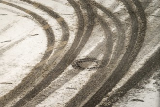 Car tire tracks curving on a snowy road surface in winter, indicating vehicle movement and winter