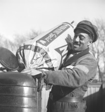 Wood gas 1945. A man at a Shell service station fills more coal into the container to fuel the wood