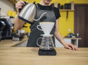 Front view female barista pouring hot water coffee filter