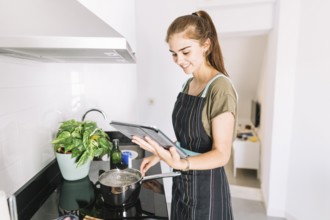 Woman preparing food by looking recipe digital tablet