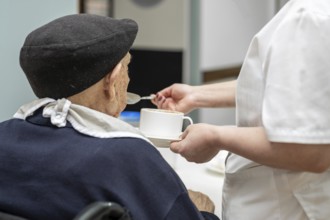 Senior man getting fed by carer in nursing home. graphy