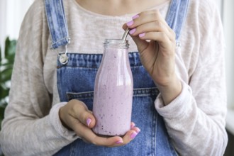 Female hands holding Blueberry smoothie topped with blueberries. Woman eating glass of breakfast