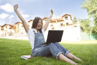 Female gets joyful emotions by talking to her friends on a conference call from notebook, she
