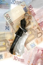 Wedding couple figurine over euro notes background, love and money